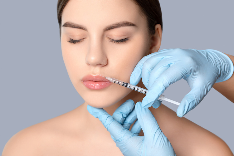 Cosmetologist does injections on the lips and on the face of a beautiful woman in a beauty salon. Women's cosmetology in the beauty salon. (Cosmetologist does injections on the lips and on the face of a beautiful woman in a beauty salon. Women's cosme