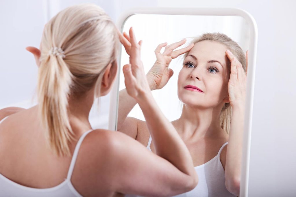 Middle aged woman admiring her facelift.   La Jolla Skin. Dr. Chaffoo.
